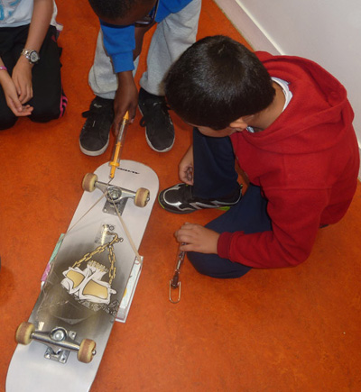 Foto: Kinder ziehen eine Last, auf der eine Skateboard liegt