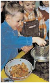 Foto: Ein Kind füllt Obst in eine kleine Weinpresse